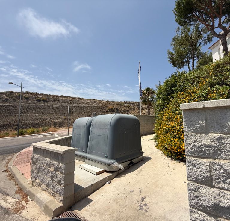 Large grey bins beside a road.